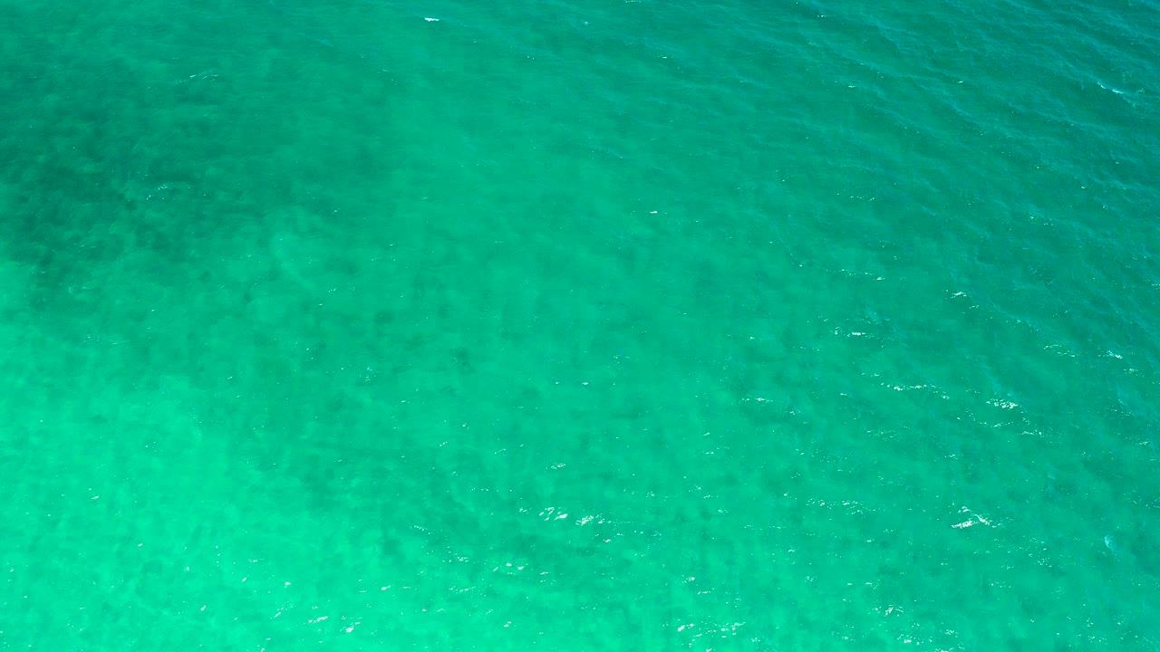 Overhead turquoise seawater with ripples and darker patches.