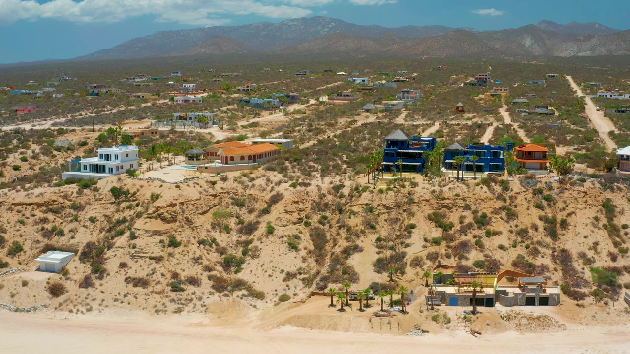 Aerial view of white and orange-roofed homes on dry slopes.