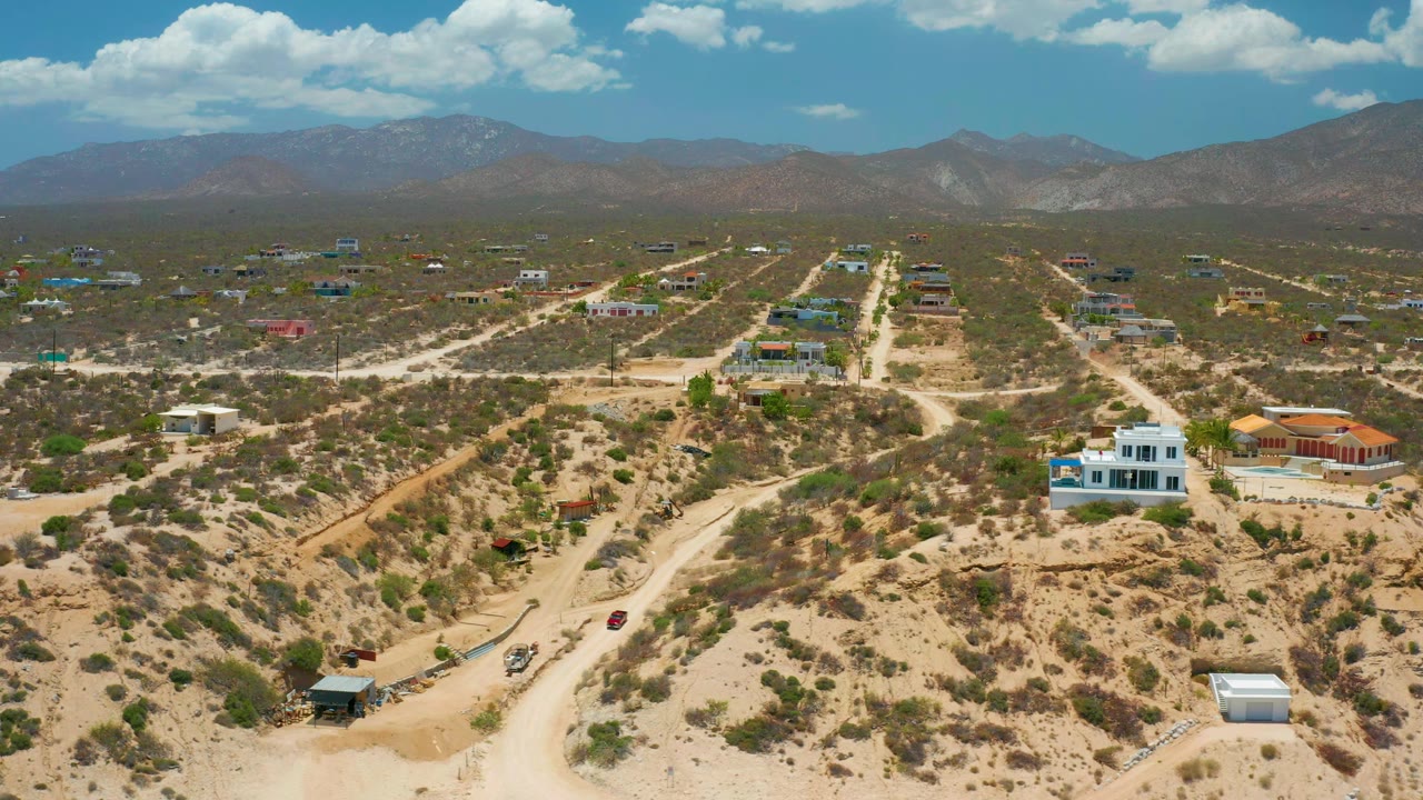 Elevated view of pale roads crossing a dry valley with houses and mountains.