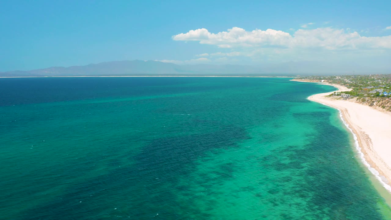 Wide aerial coastline with turquoise shallows and pale beach.