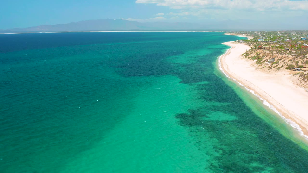 Aerial frame from El Sargento La Ventana, Mexico, with the curved white shoreline tighter on the right, green-blue shallows in the center, and no visible people.