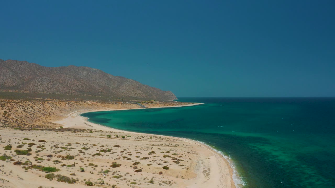 Aerial shoreline with pale beach, turquoise water, and clear sky