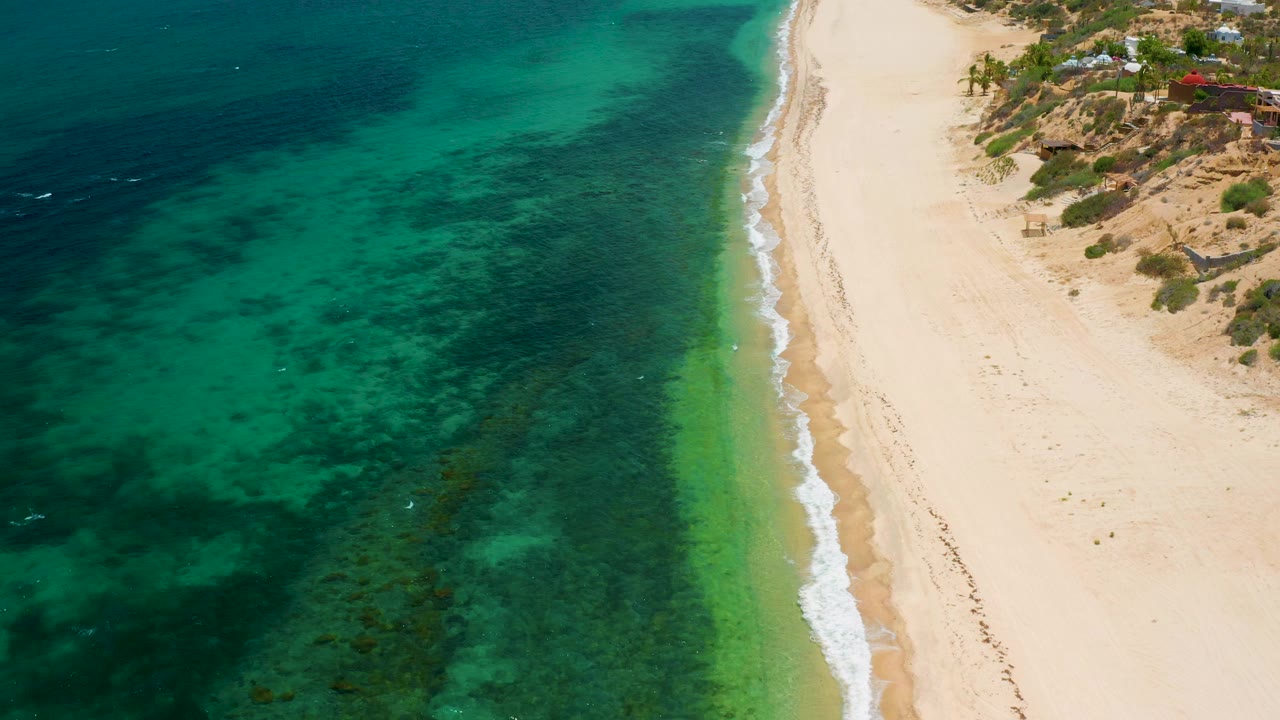 Clear green water and narrow surf line along sand