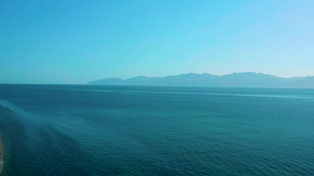 Blue ocean surface fills the frame below a high horizon, with the El Sargento La Ventana coastline area represented by distant land and no visible people.