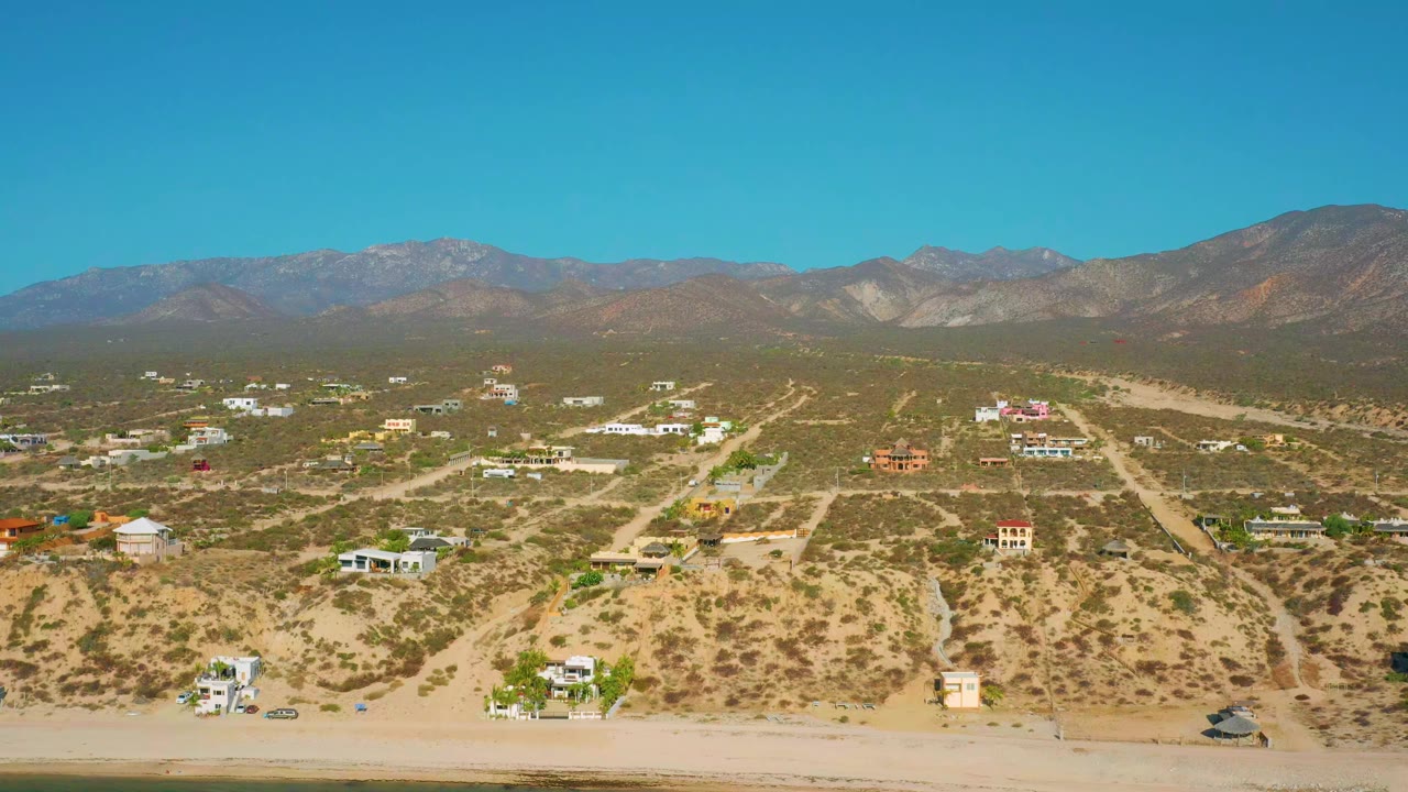 Wide desert settlement with houses, scrub plants, roads, and mountain ridge
