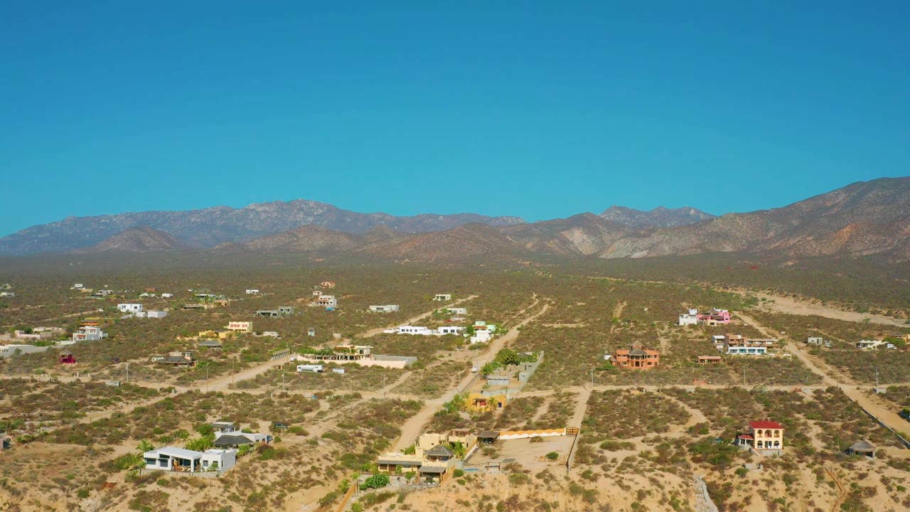 Elevated desert neighborhood view with dirt tracks and low houses.