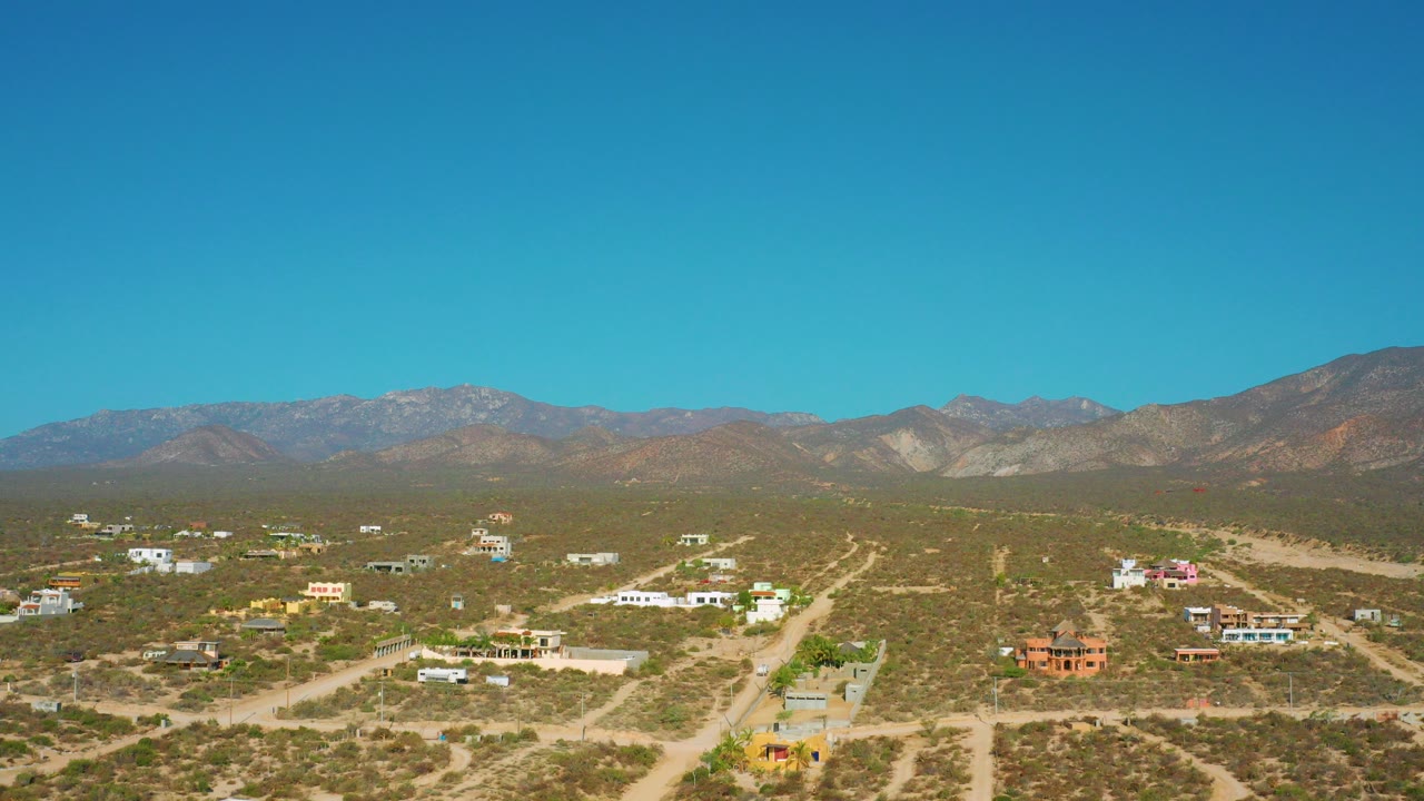Opening frame of El Sargento La Ventana, Mexico, showing scattered desert homes, pale dirt roads, scrubland, mountain ridges, and no visible people.
