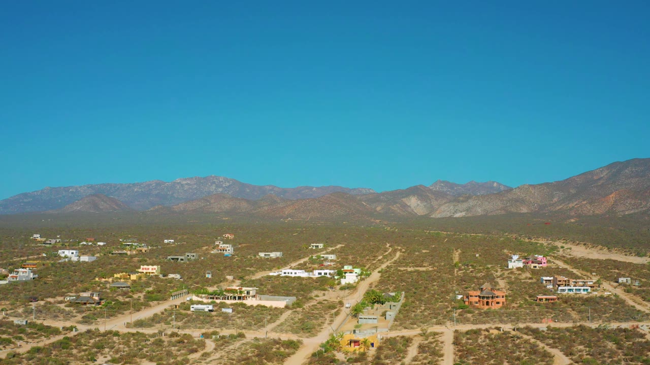 Wide desert neighborhood with low houses, roads, and mountain backdrop