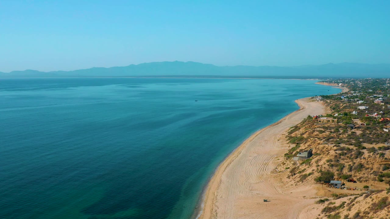 Ocean shoreline aerial with darker water bands and dry beach hills.