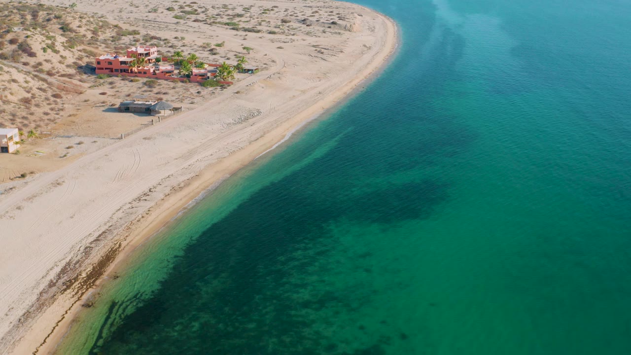 High aerial view of empty beach beside clear green-blue sea