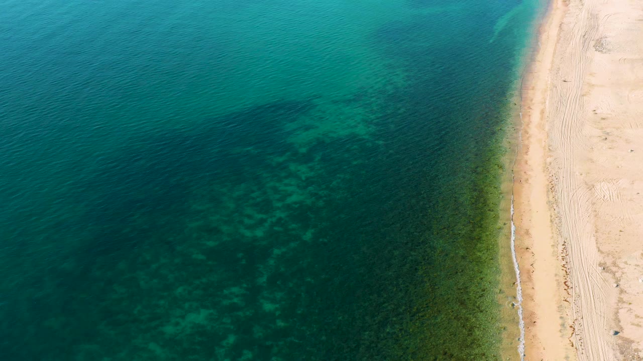 Turquoise sea and narrow beach seen from above.