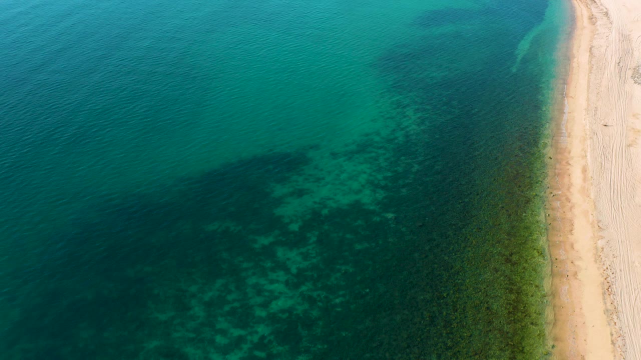 Aerial view of turquoise water beside a white sand beach