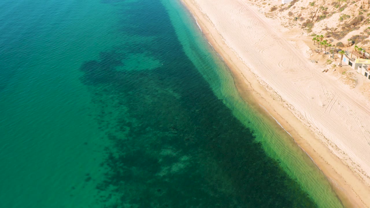 Diagonal beach edge with green water and submerged dark areas