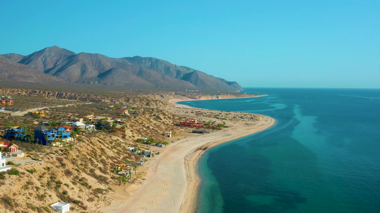 Mountain-backed coastline with beach, ocean, and scattered homes