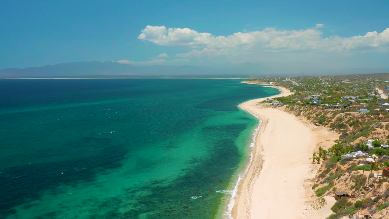 Long beach and turquoise shallows under a cloudy sky