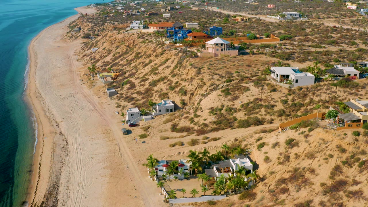 The second frame holds an elevated angle on El Sargento La Ventana, with the beach curving beside sandy hillside lots and no visible people.