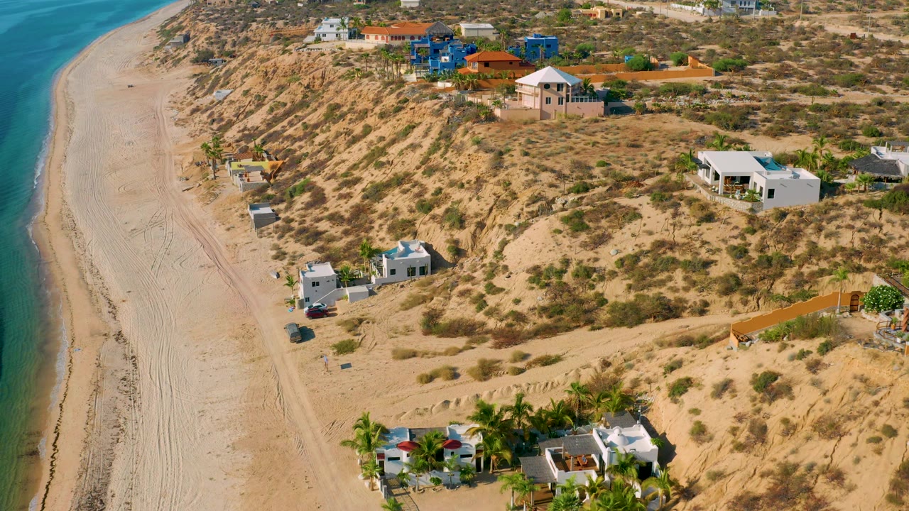 Drone view of beach, scrub dunes, and homes near the shore