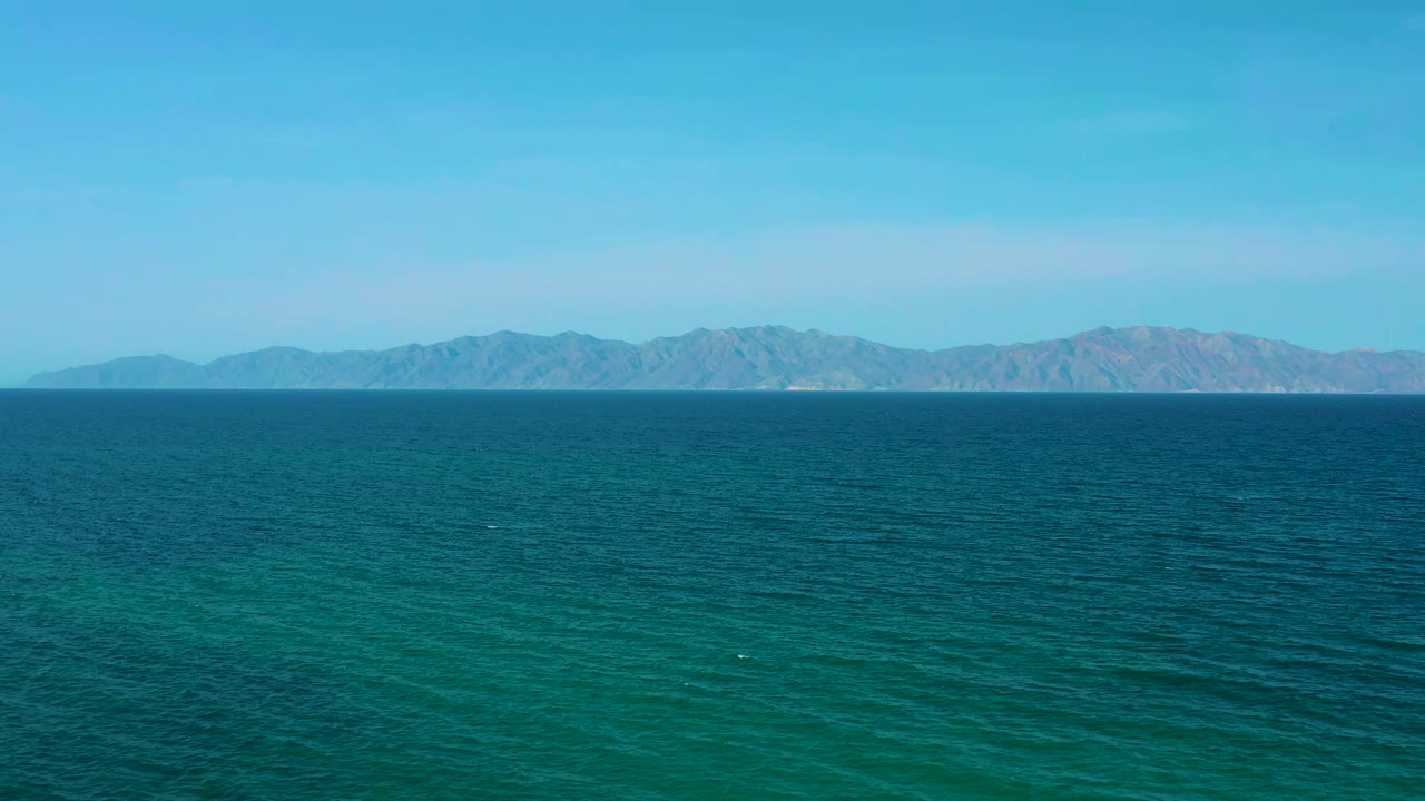 Wide ocean surface with mountains stretching across the horizon