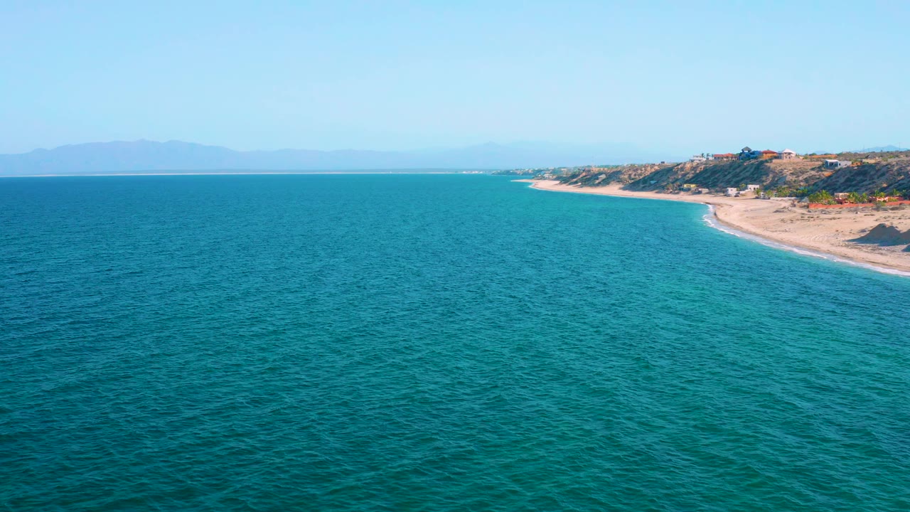 Rippling ocean with beach and coastal hills along the right side.