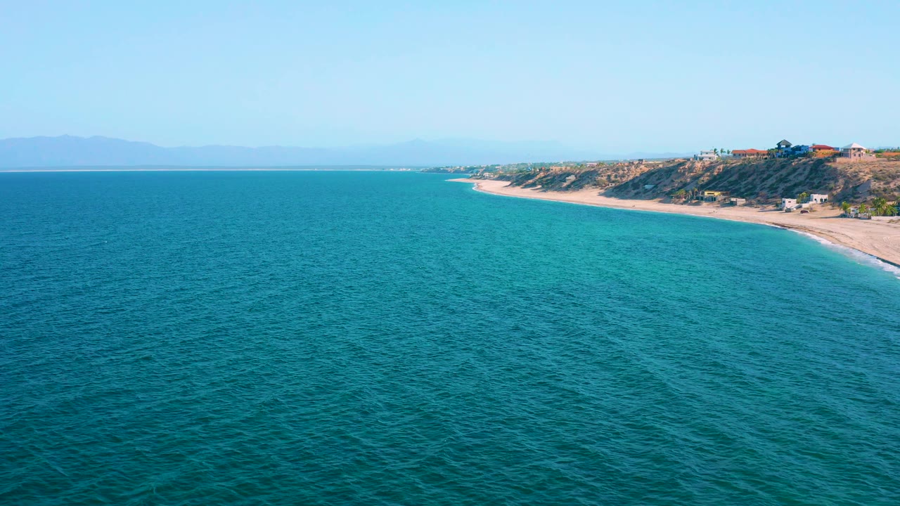 Aerial coastline view with turquoise water and a sandy beach curving past bluffs.