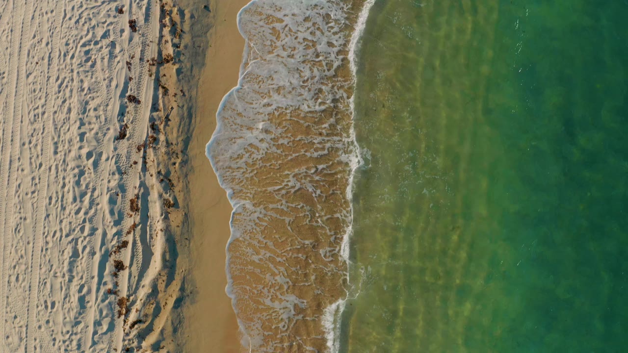 Aerial shoreline with foamy wave edge and clear water
