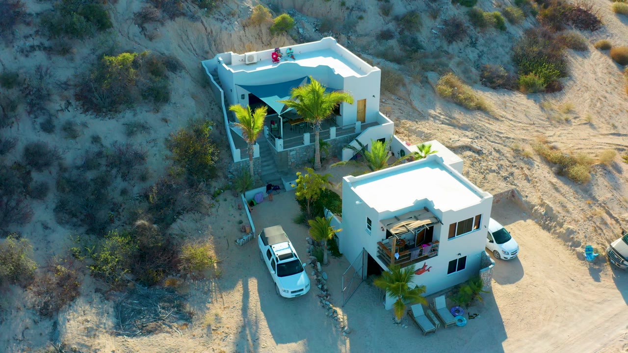 Drone view of white homes with cars and desert brush