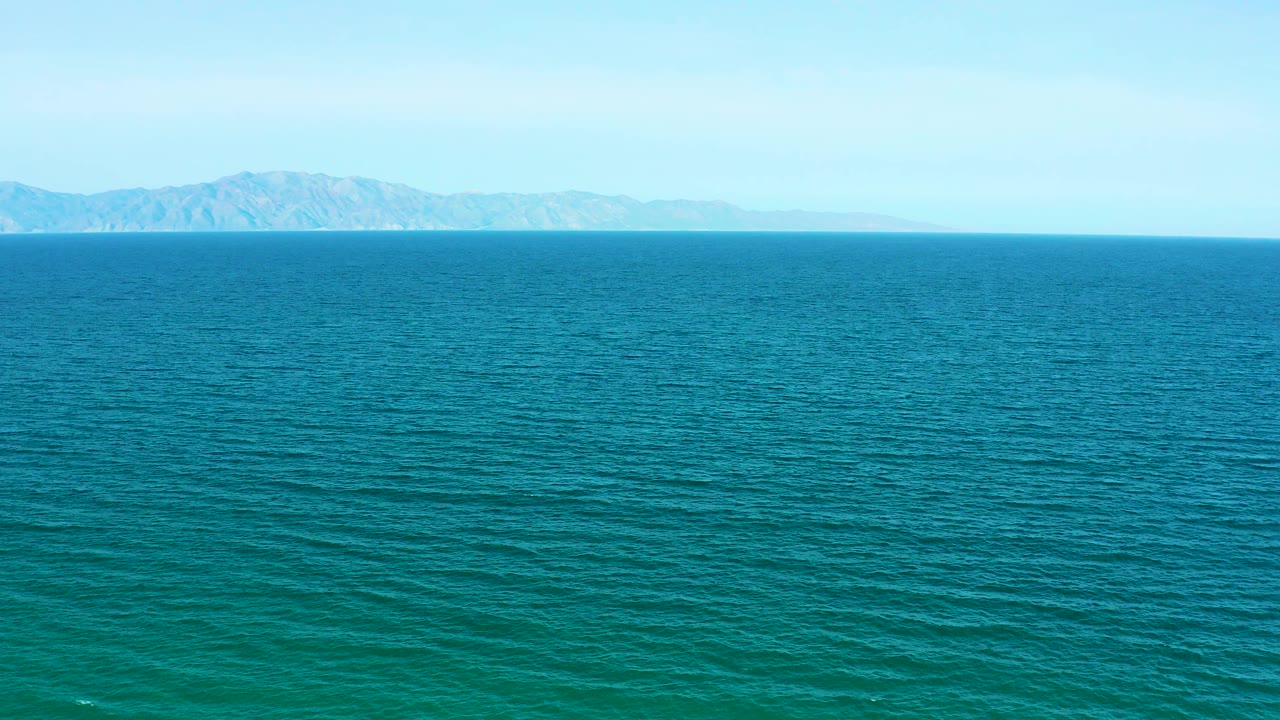 Wide blue-green ocean with distant low mountains on the horizon