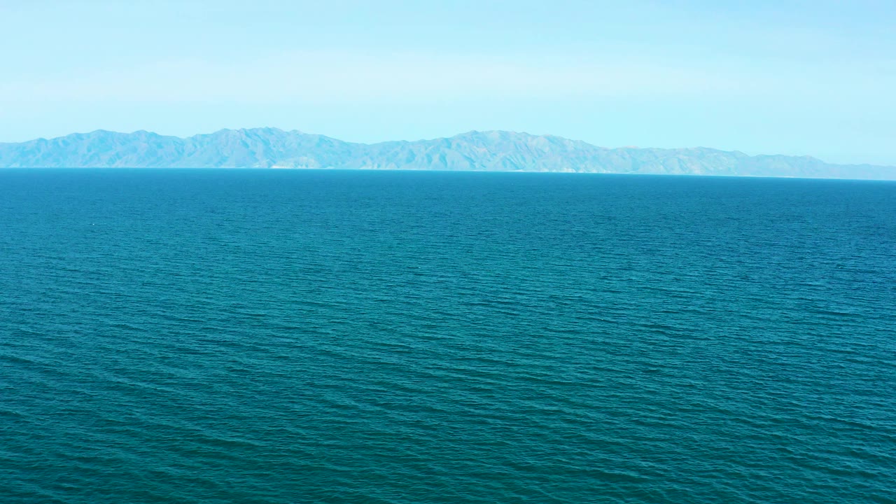 Turquoise sea with distant mountains under a pale blue sky
