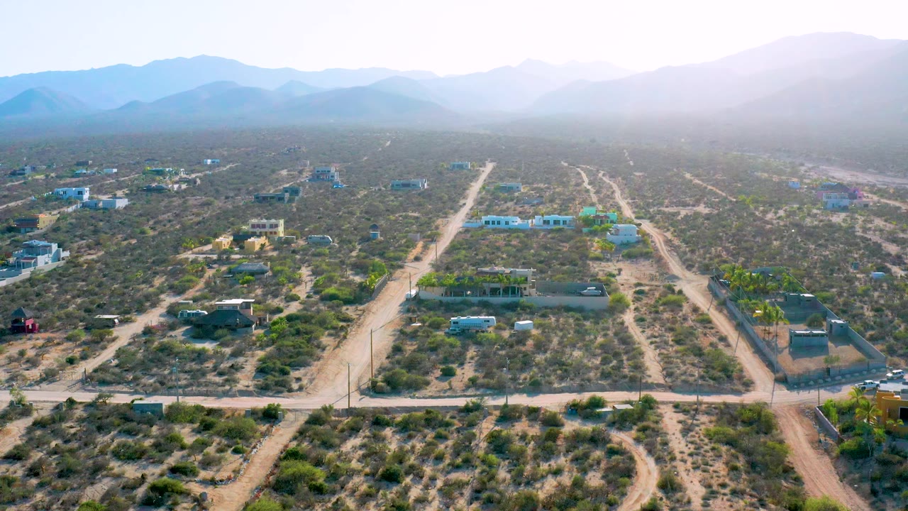 Third frame over El Sargento La Ventana, Mexico, showing a broad scrubland grid, several isolated structures, dirt roads running toward the mountains, and no visible people.