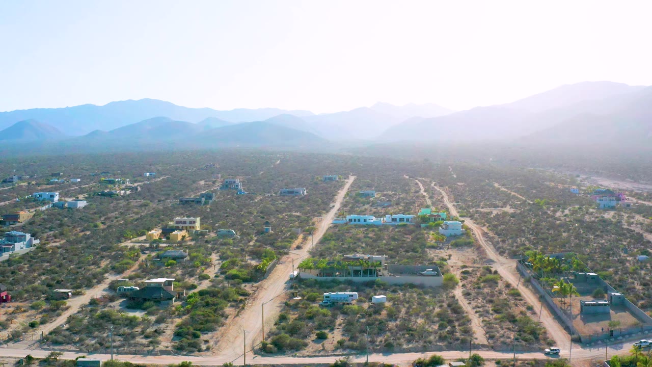 Elevated view of pale dirt roads running past houses and desert vegetation.