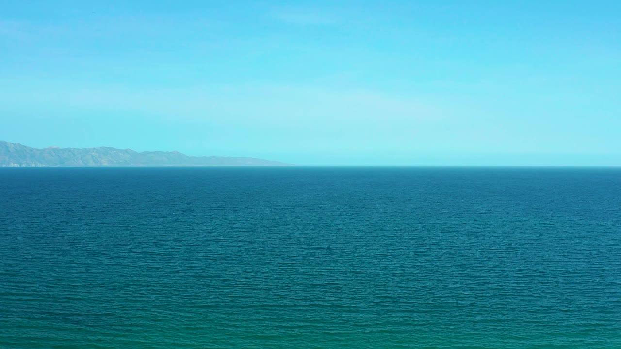 Blue-green ocean view at El Sargento La Ventana, Mexico, with a level horizon, distant coastline toward the right, and no visible people.