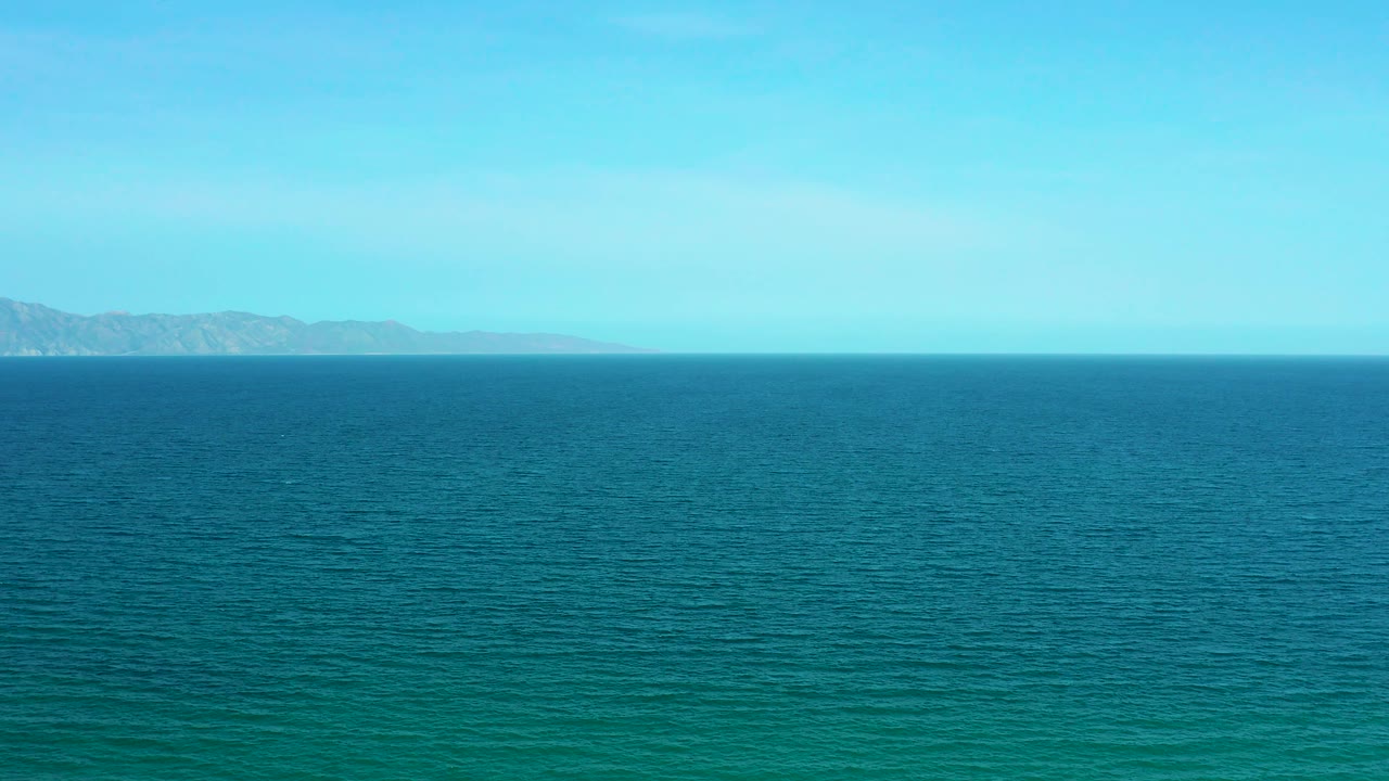 Expansive ocean surface with distant land at both sides of the horizon.