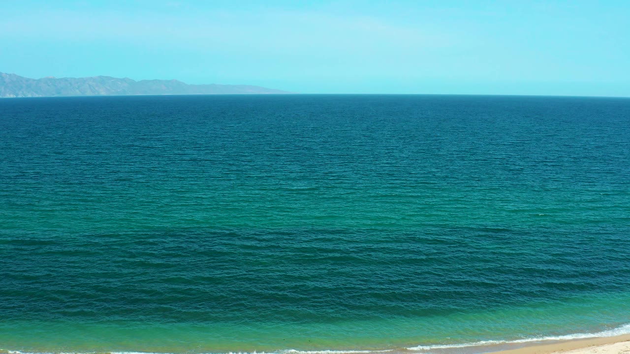 Wide blue ocean with sandy beach at the bottom edge