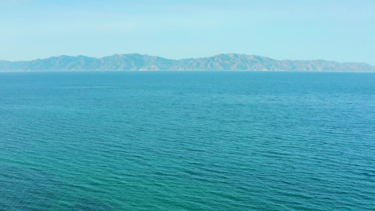 Wide elevated view over blue water toward distant mountains in El Sargento La Ventana, Mexico, with no visible people or boats.
