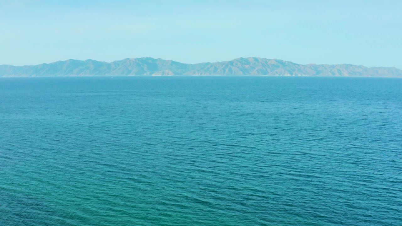 Calm sea surface shows fine ripples beneath a distant coastal mountain range near El Sargento La Ventana, Mexico, with no visible people.