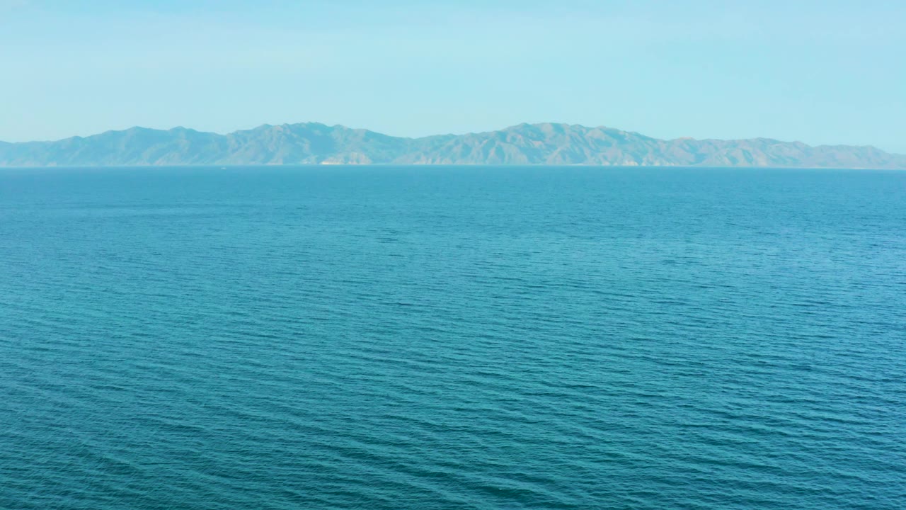 Open turquoise water leads to a rugged distant coast range in El Sargento La Ventana, Mexico, with no visible people or vessels.