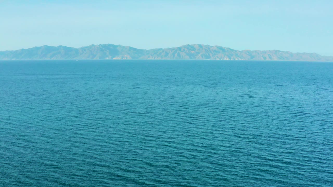 A wide sea view in El Sargento La Ventana, Mexico shows textured turquoise water and mountains stretching across the background, with no visible people.