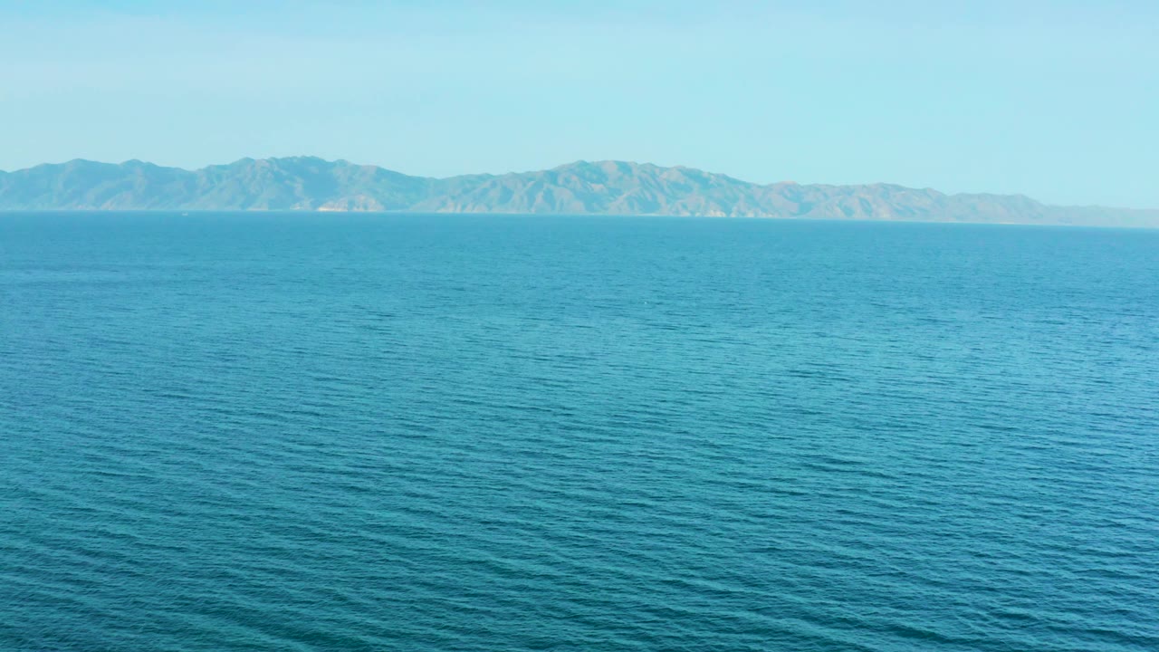 Fourth frame of El Sargento La Ventana, Mexico, holding a level horizon where blue ocean meets low mountains and a pale blue sky, with no visible people.