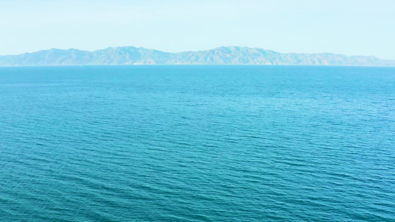 A broad expanse of rippled blue ocean sits under soft daylight, with far hills stretching across the horizon near El Sargento La Ventana, Mexico, and no visible people.