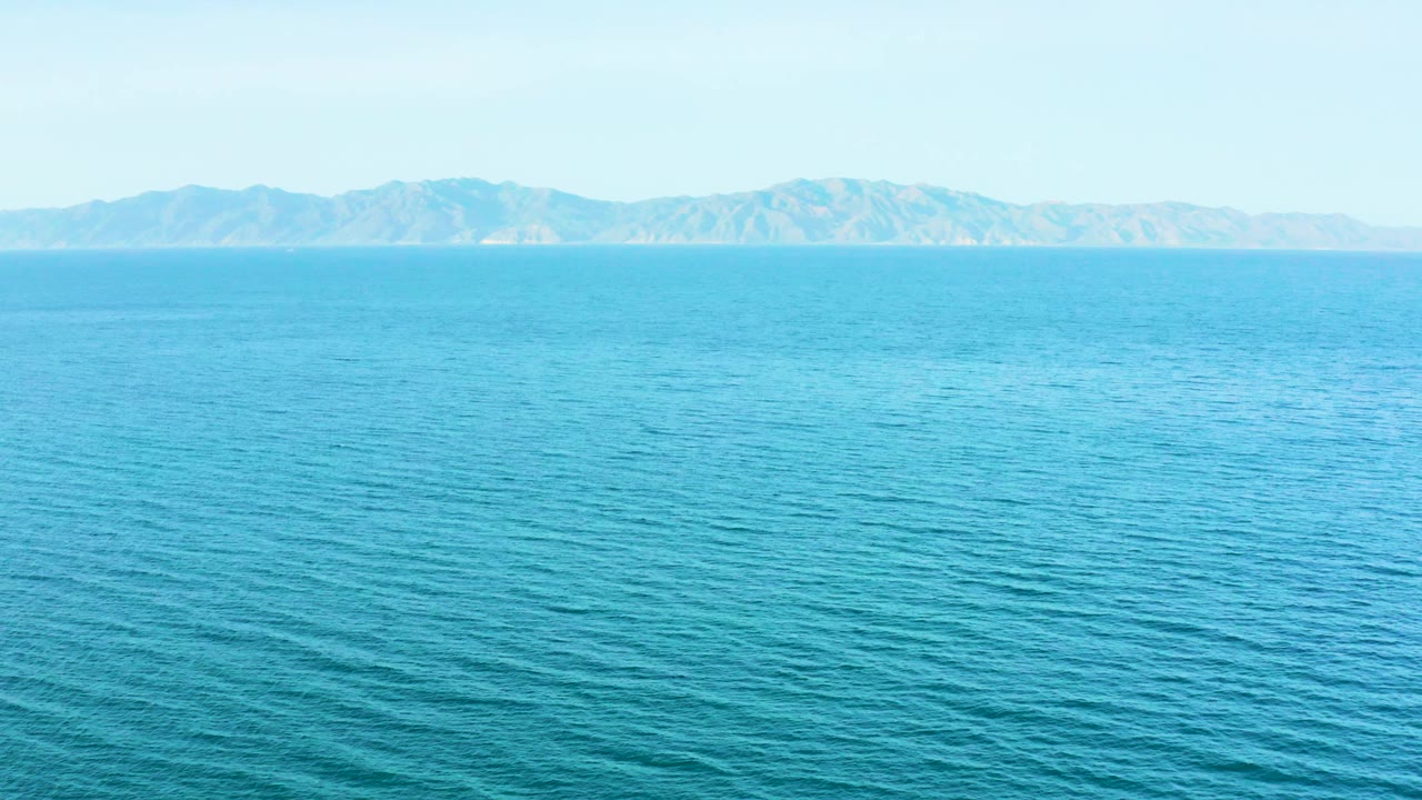 Mid-clip view of blue ocean foreground and midground, a thin horizon band, and low mountains in the distance at El Sargento La Ventana, Mexico, with no visible people.