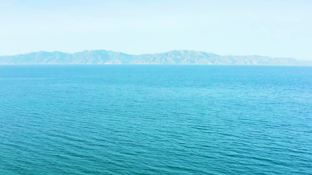 Wide view of the blue sea near El Sargento La Ventana, Mexico, with a faint mountain range stretching across the background and no visible people.