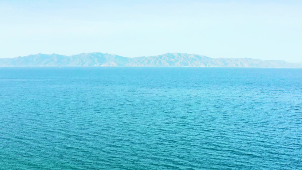 Mid-clip frame of El Sargento La Ventana ocean water, with textured blue surface in the foreground, mountains on the horizon, and no visible people.