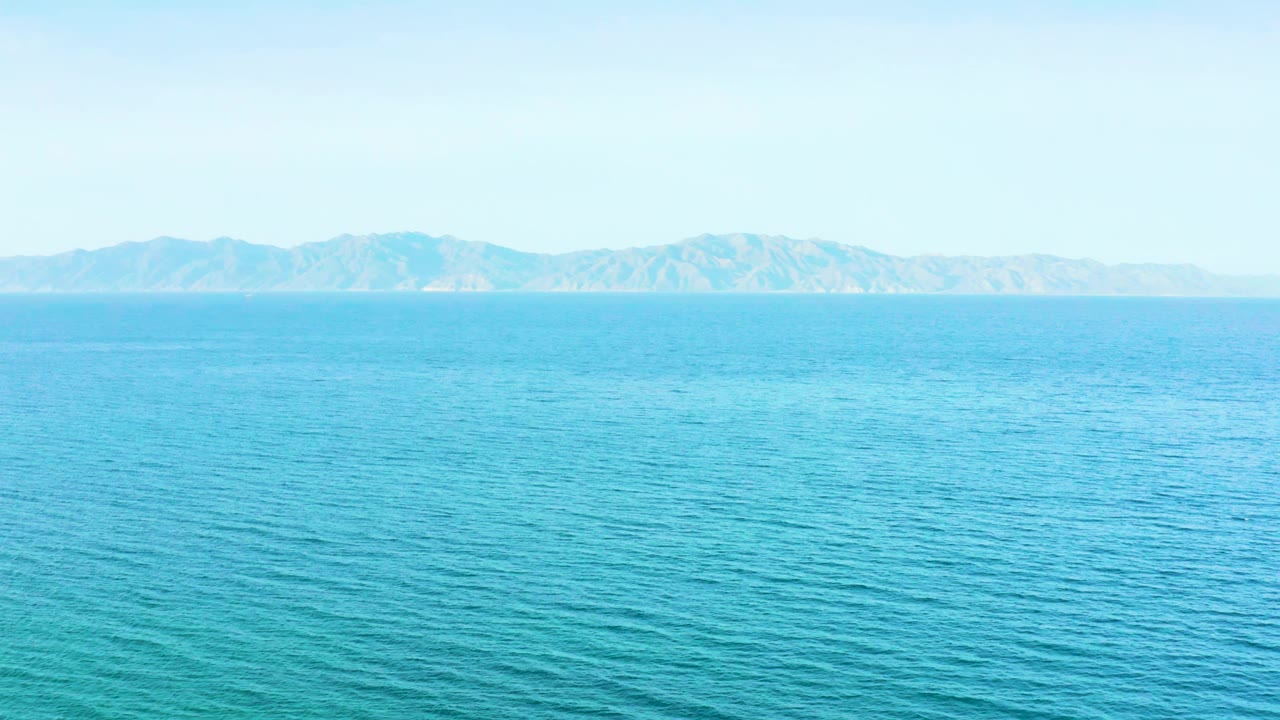 Blue ocean fills the frame with the mountain ridge sitting low on the horizon in El Sargento La Ventana, Mexico, and no visible people.