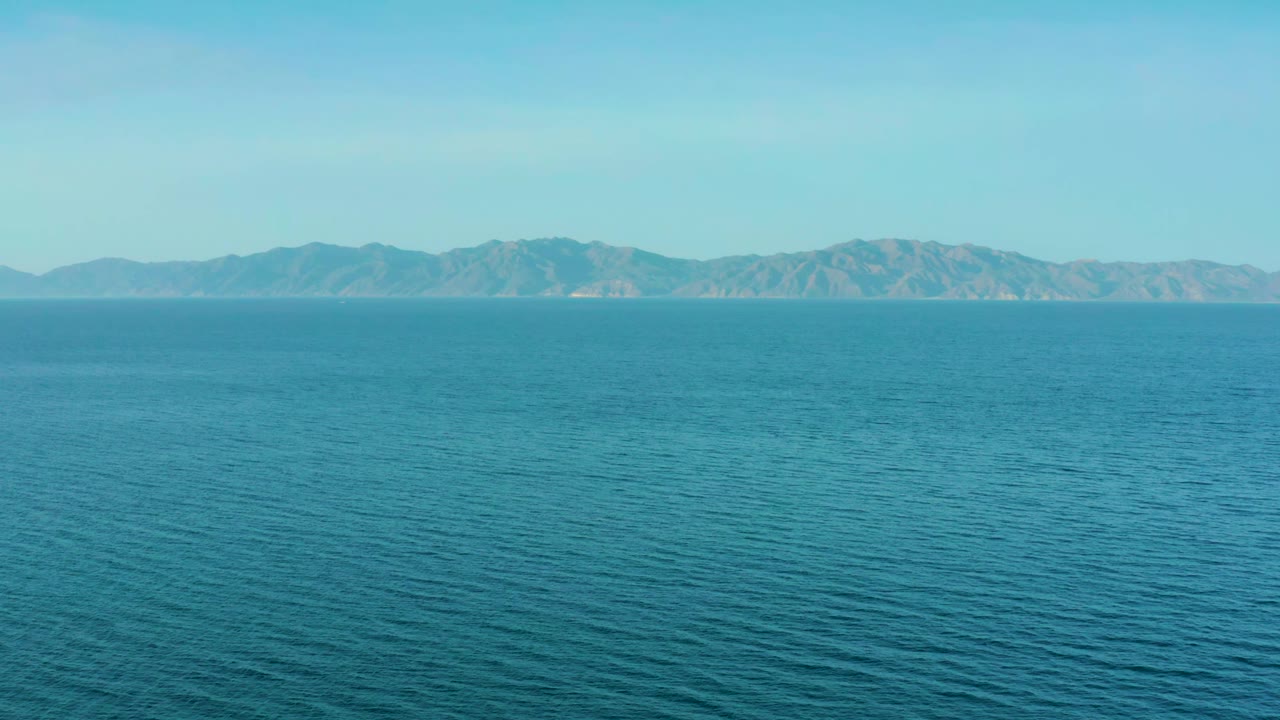 Open water ripples leading toward a long mountain ridge.