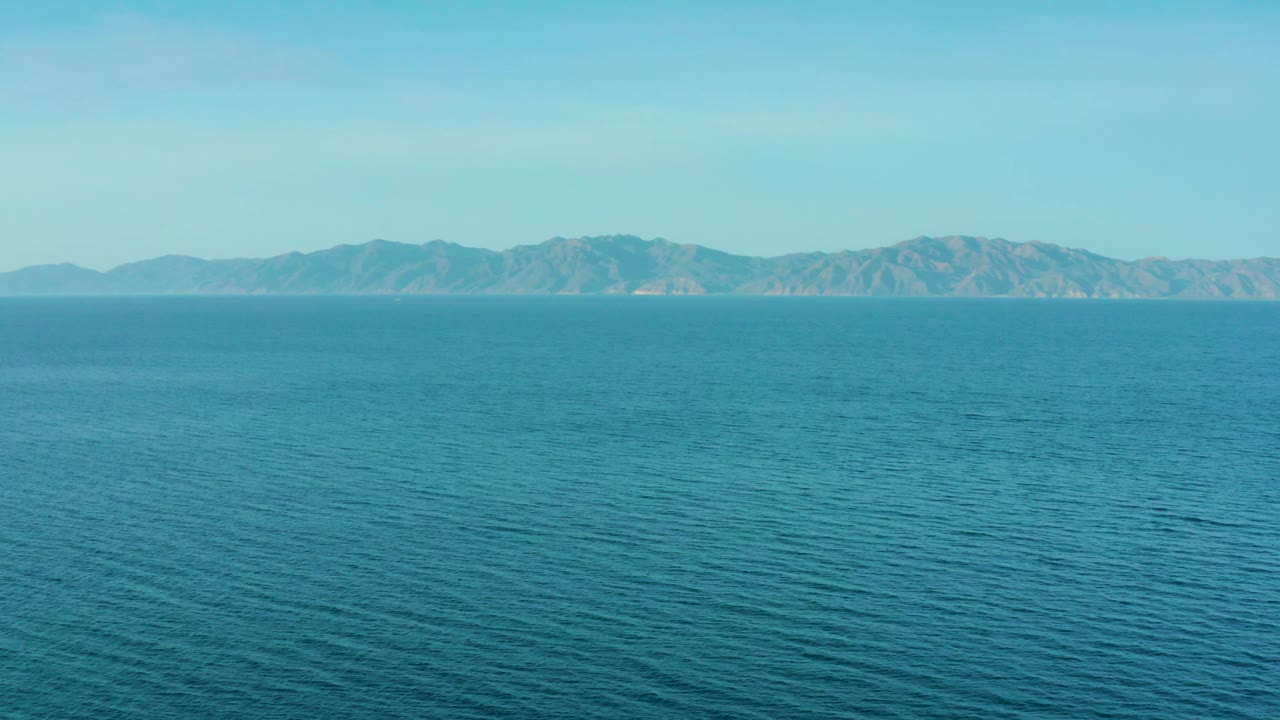 Open blue water sits below hazy distant hills in El Sargento La Ventana, Mexico, with a simple sky and no visible people.