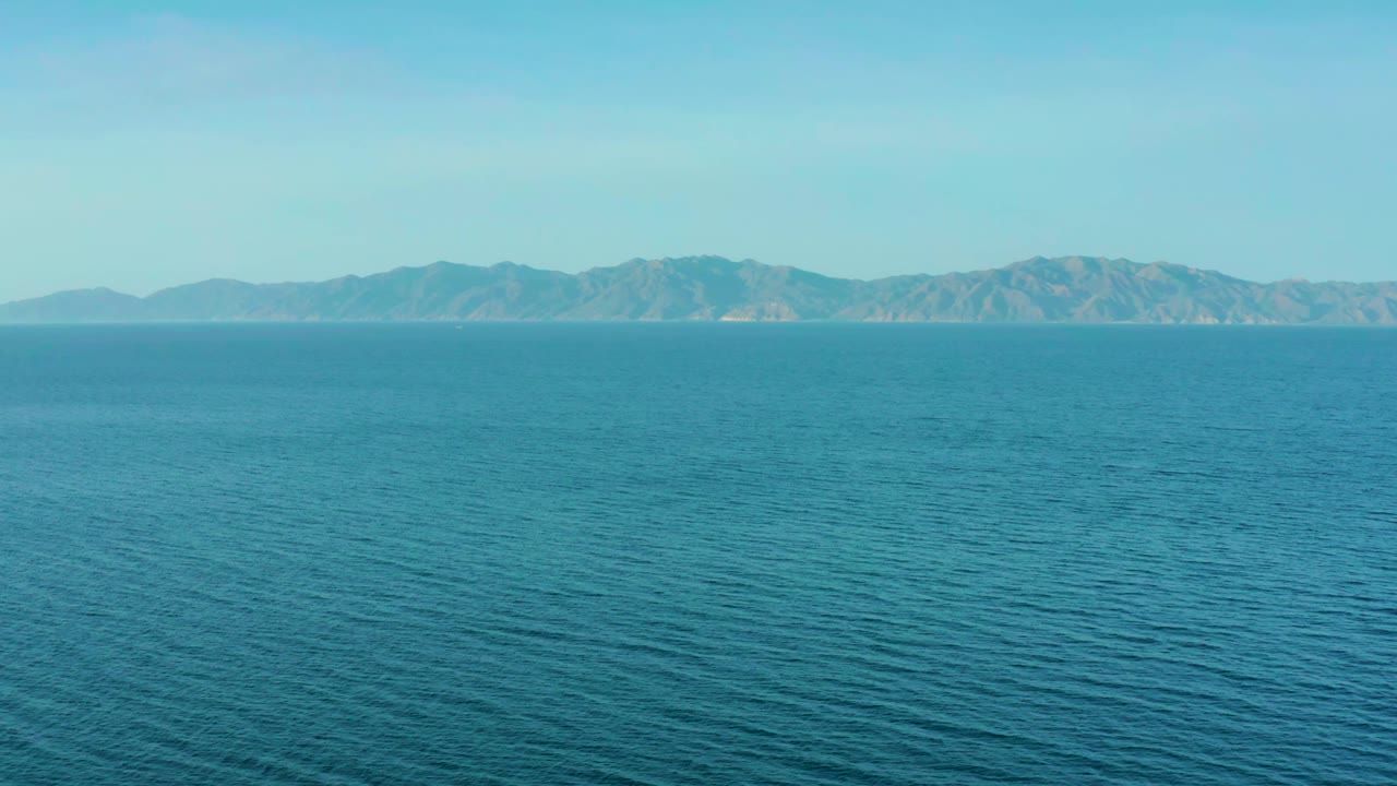 At 0:01, the El Sargento La Ventana frame keeps the ocean dominant in the foreground while the distant mountain ridge sits across the upper horizon, with no visible people.