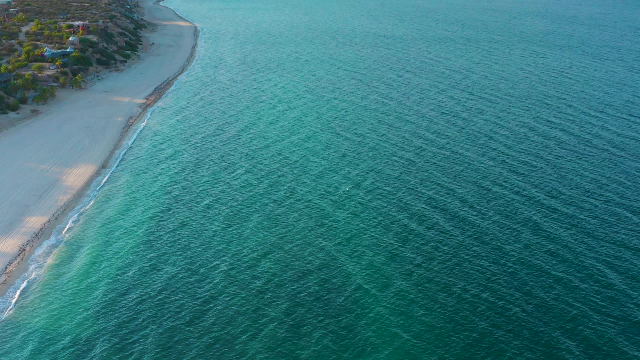 High view of curving beach with clear blue-green sea