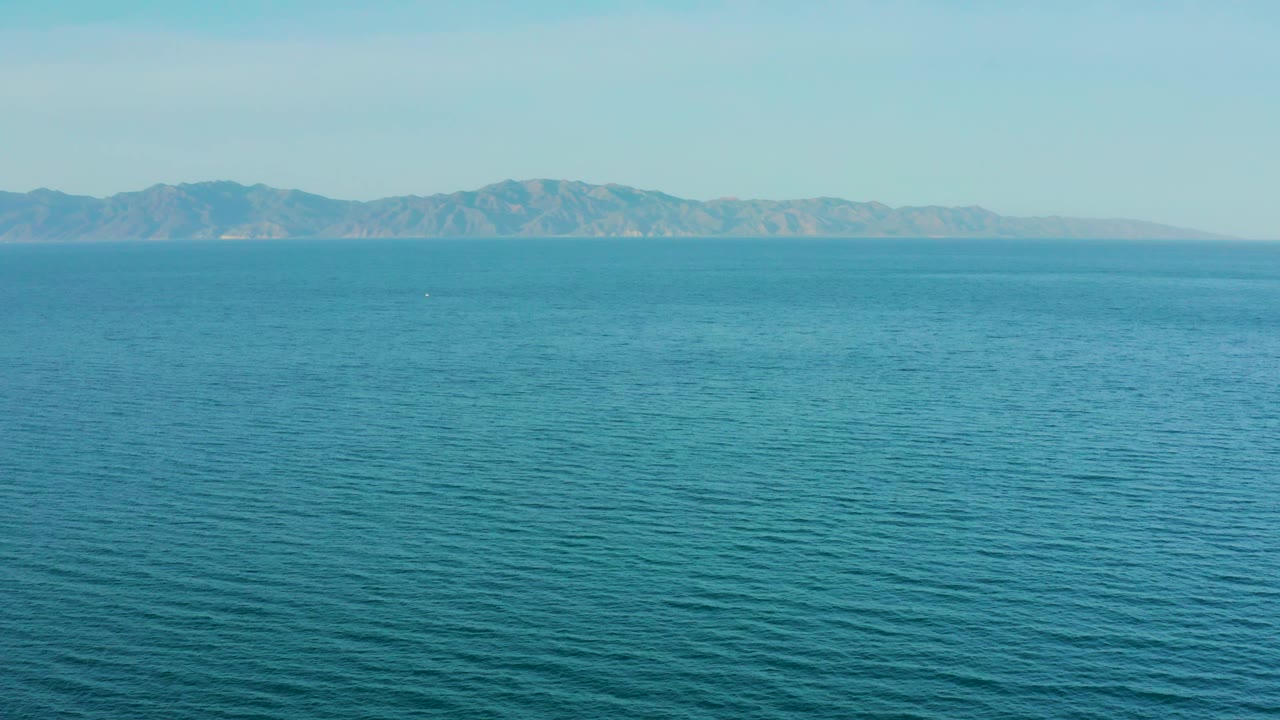 A wide elevated view shows open blue ocean and a low mountain coast at El Sargento La Ventana, Mexico, with no visible people or vessels.