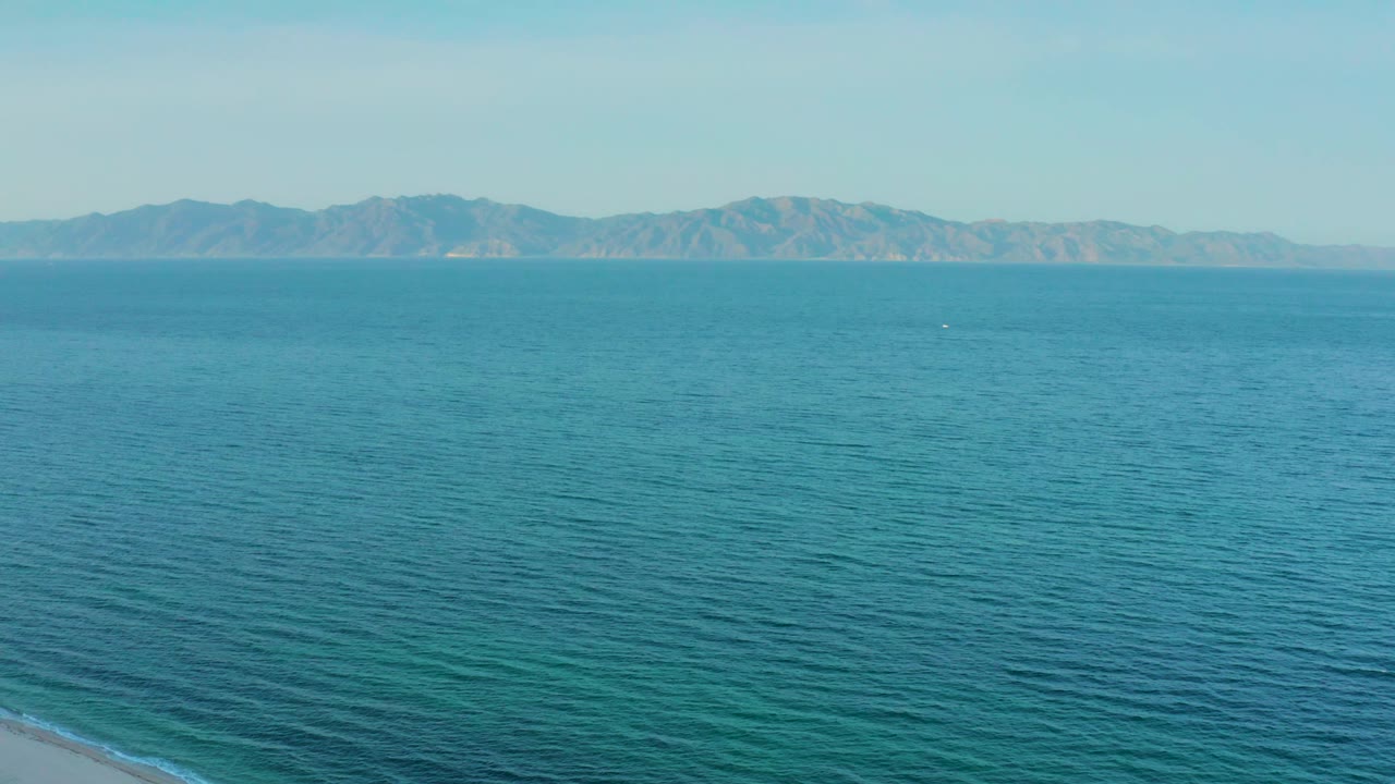 Elevated view over blue water near El Sargento La Ventana, Mexico, with low mountains spanning the background and no visible people or vessels close to camera.
