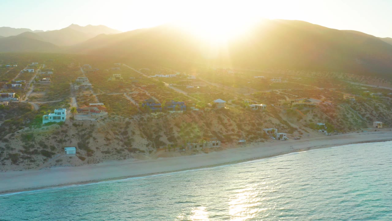 Beach and hillside settlement under low morning sun.